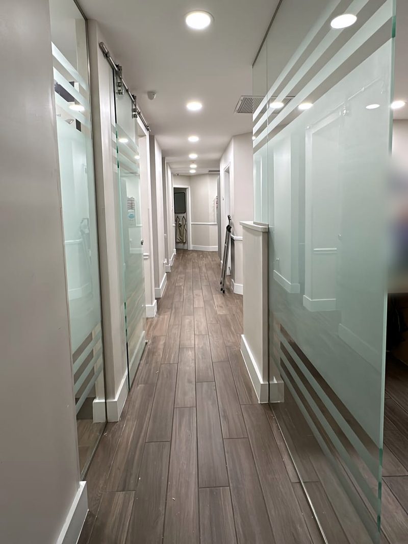 Office hallway with frosted-stripe glass walls and a sliding glass door on a top track