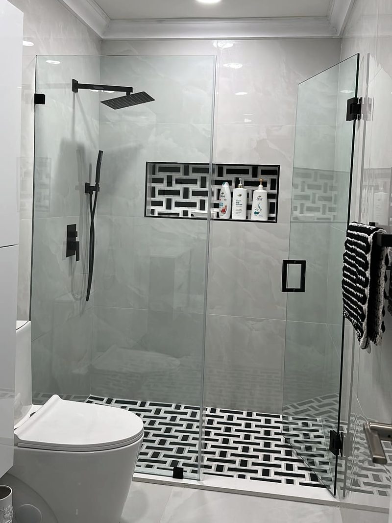Frameless glass shower enclosure with matte black hinges, handle and rain shower head